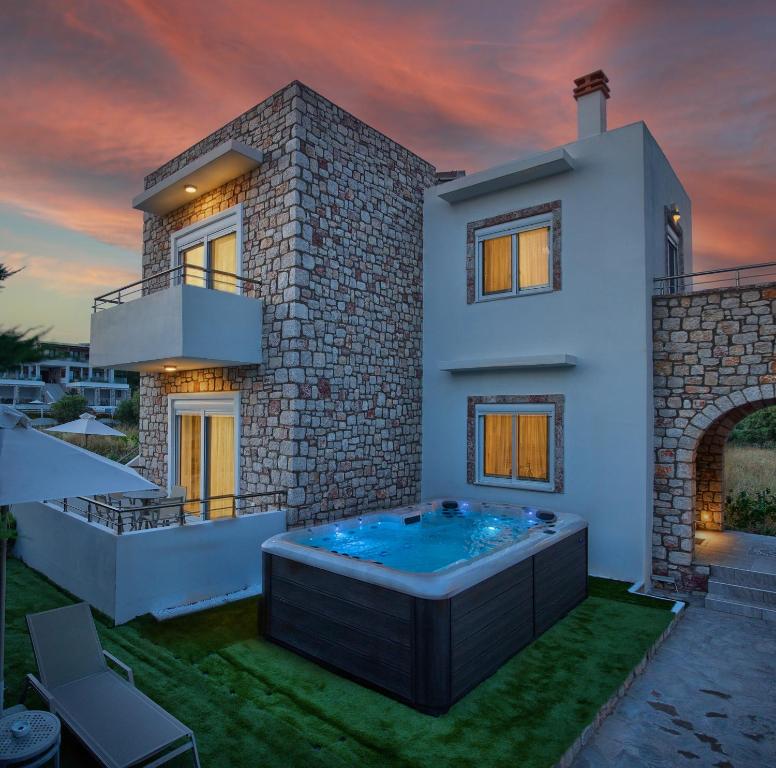 a house with a hot tub in the yard at Haraki Stone Apartments in Haraki