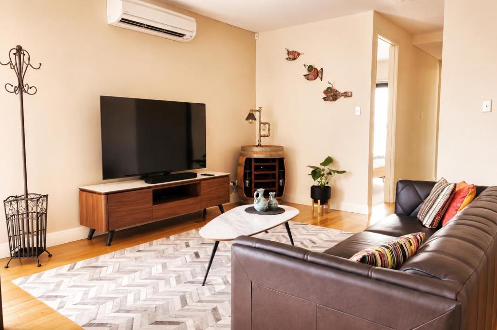 a living room with a couch and a flat screen tv at Rooftops on HenryCentre of West End Cafes in Fremantle