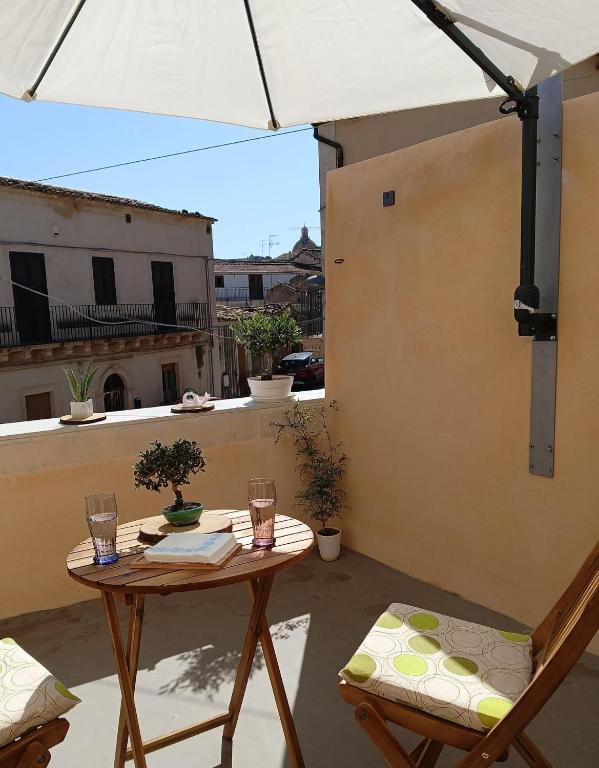 a table and chairs on a balcony with an umbrella at Oasi nel cuore di Noto in Noto