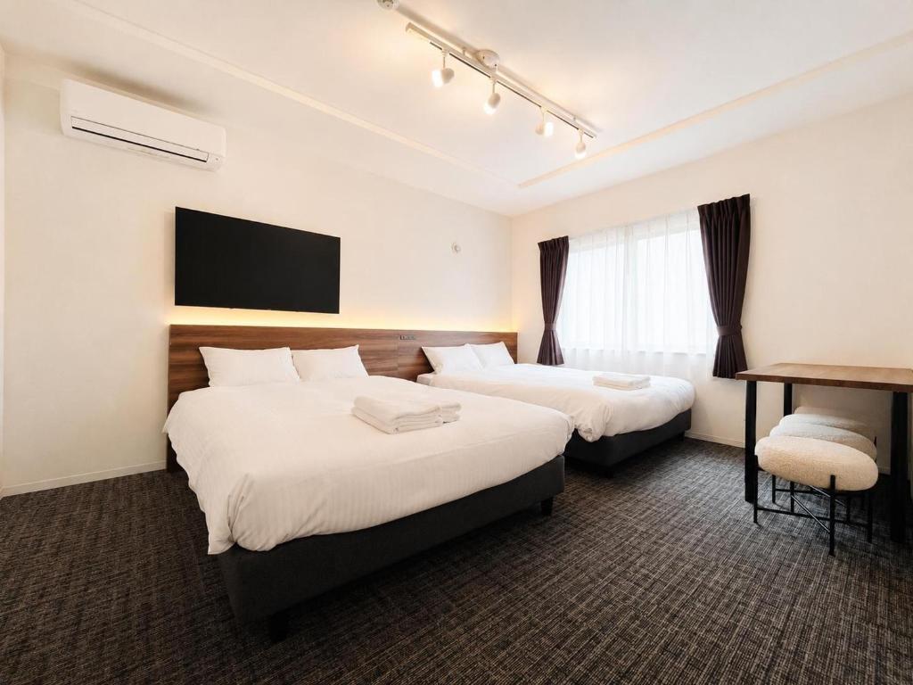 a hotel room with two beds and a desk at Hotel ONE'S RESIDENCE in Sapporo