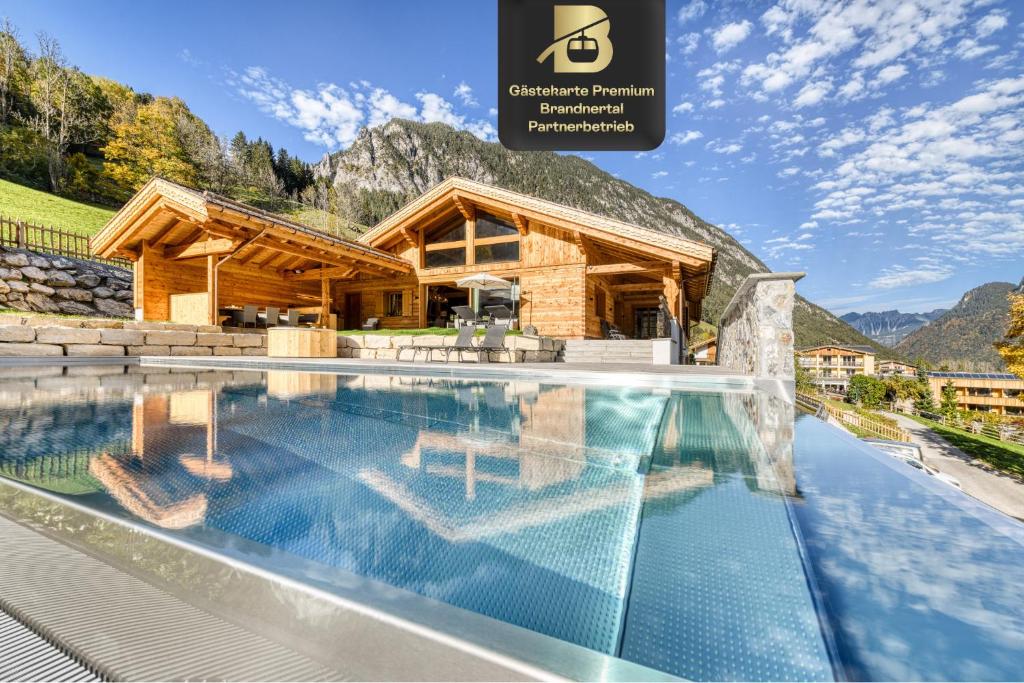 a log house with a swimming pool in front of it at Chalet GM - Gesamtes Haus by A-Appartments in Brand