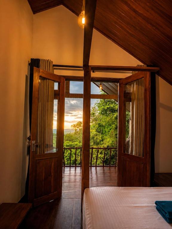 an open door to a room with a bed and a balcony at Forest River Escape Ella in Ella