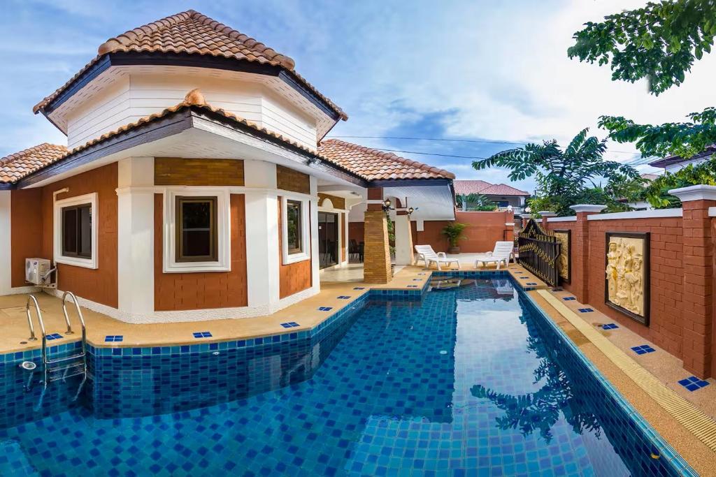 a villa with a swimming pool in front of a house at Villa Marcello in Pattaya South