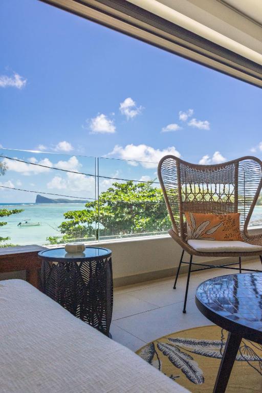 a room with a large window with a chair and a table at Luxury Beachfront Apartment in Pereybere