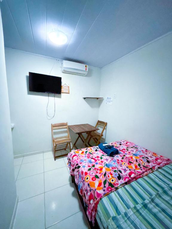 a bedroom with a bed and a table and a tv at Suítes Jacumã in Conde