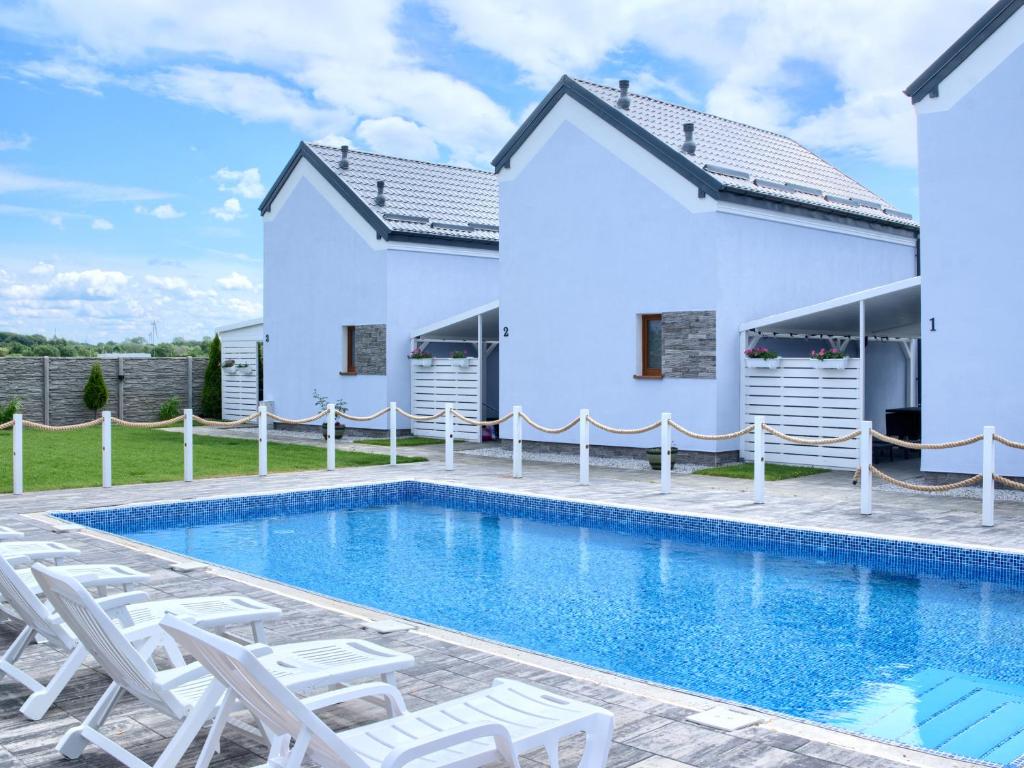 a villa with a swimming pool and chairs at Domki Venus z basenem in Ustronie Morskie
