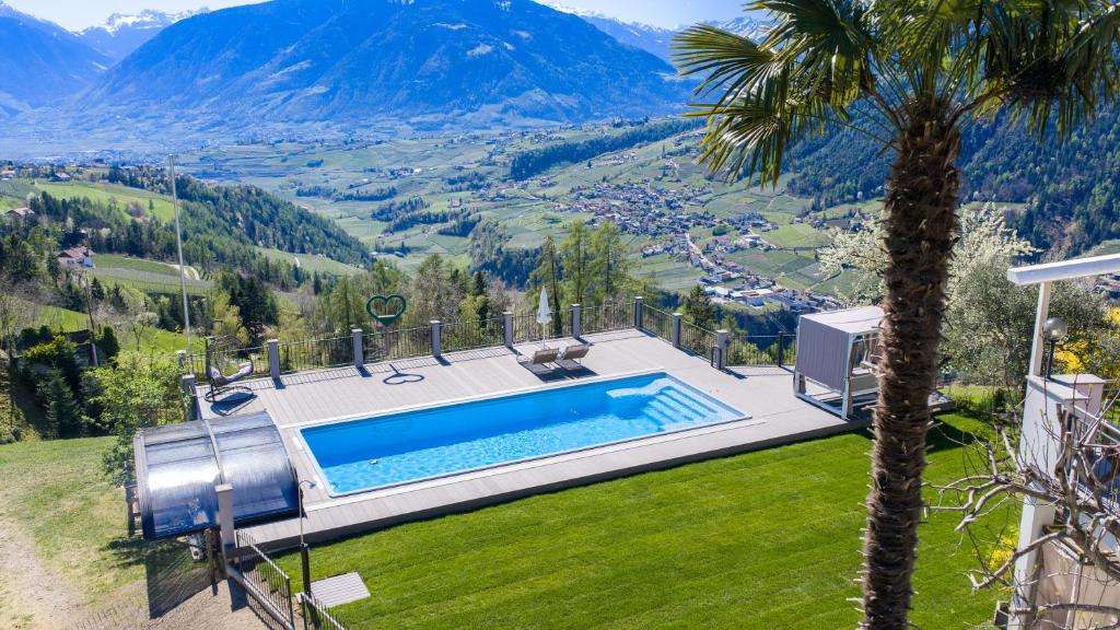 a villa with a swimming pool and a palm tree at Gasserhof Garni & Apartment in Schenna