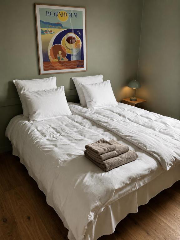 a large white bed with towels on top of it at Albi's Sandvig Boutique Hotel in Sandvig