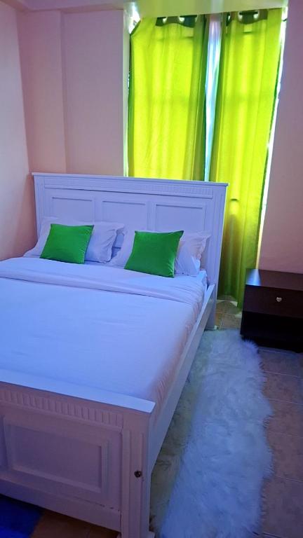 a white bed with green pillows in a room at Tee Luxury Homes in Naivasha