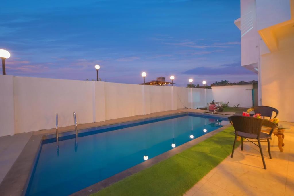 a swimming pool with a table and chairs next to a building at ll VIBE WITH US II BIG DADDY VILLA II 6BHK II AC II PRIVATE POOL II in Lonavala