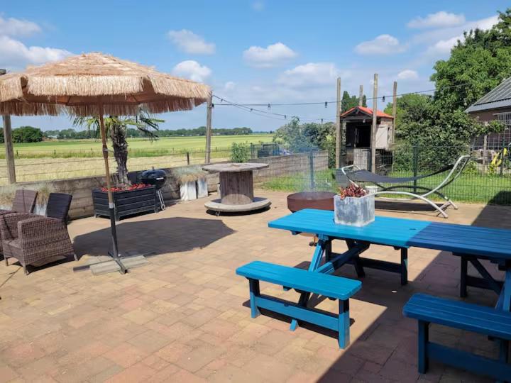 a picnic table and an umbrella on a patio at Het Atelier Huis - Geschikt tot 8 personen in Maasbommel