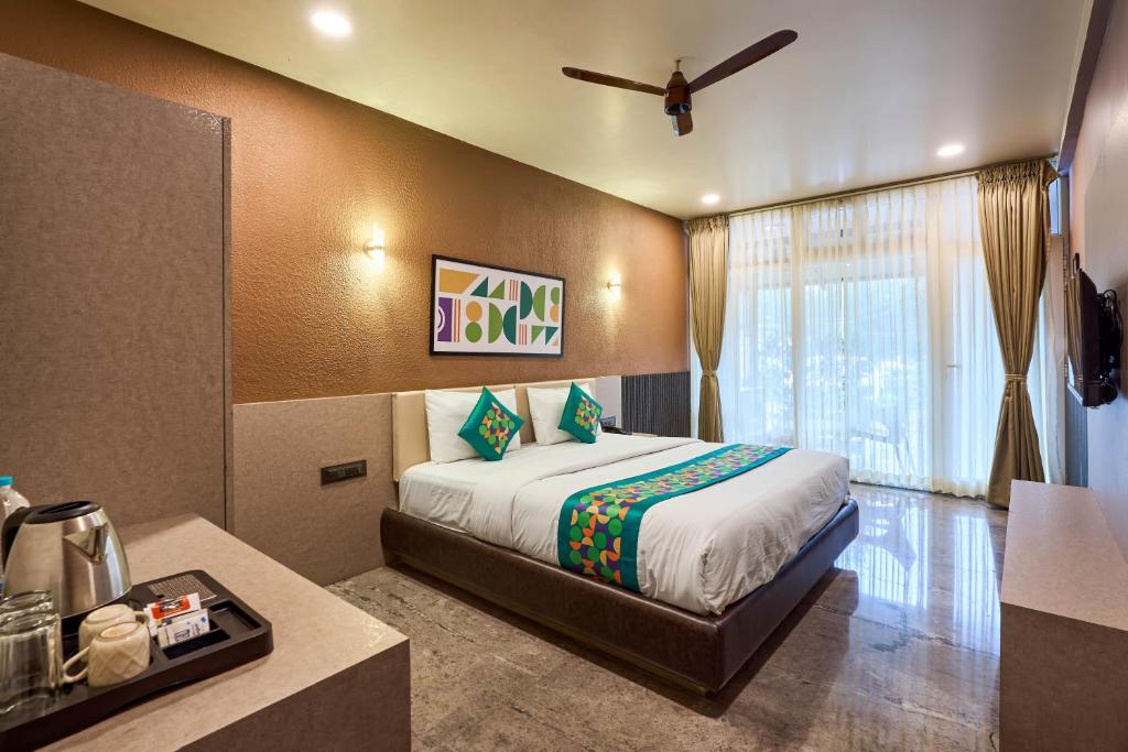 a hotel room with a bed and a window at Treebo Sky Vista Suites with Hill View in Chikmagalūr