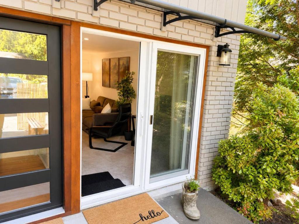 a sliding glass door on a house with a living room at Modern North Van Escape with 2BR BBQ Workspace in North Vancouver