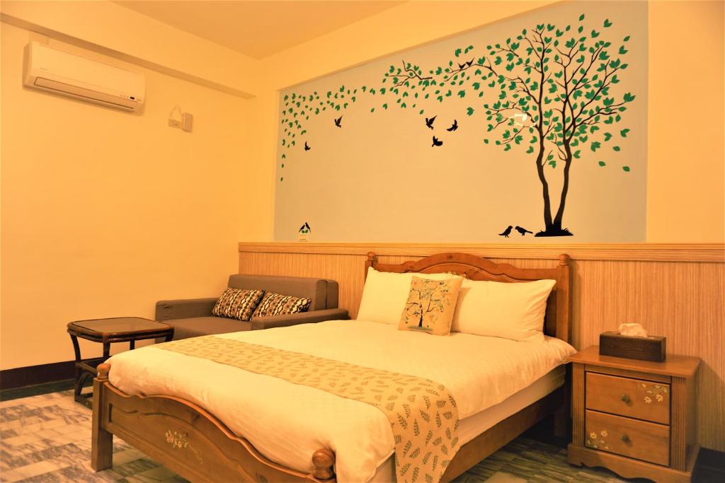 a bedroom with a bed and a tree on the wall at Snail Trail B&B in Taitung City