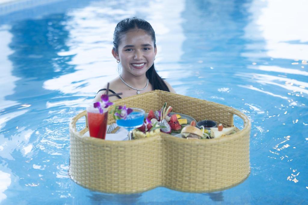 a girl in a swimming pool with a basket of food at Cambana Poipet Hotel in Krong Poi Pet