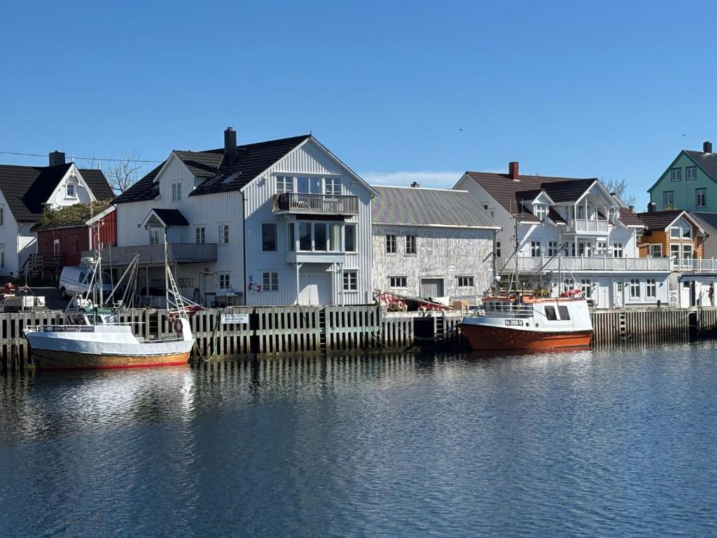 two boats are docked in a marina with houses at Henningsvær Harbour Haven in Henningsvær