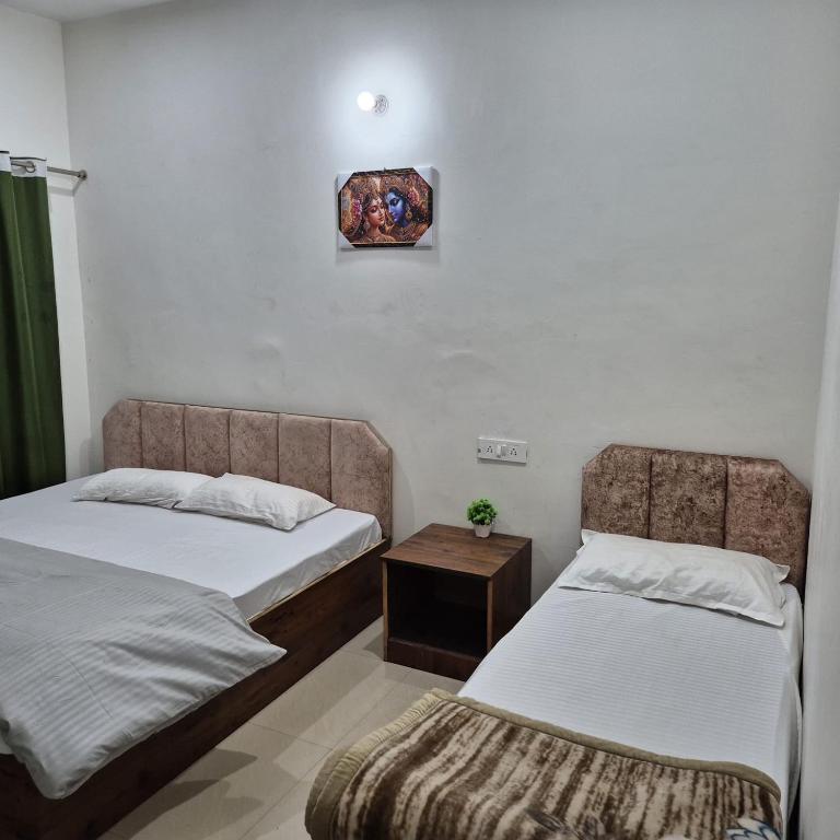 ein Zimmer mit zwei Betten und einem Tisch darin in der Unterkunft Devadidev Retreat in Gupta Kāshi