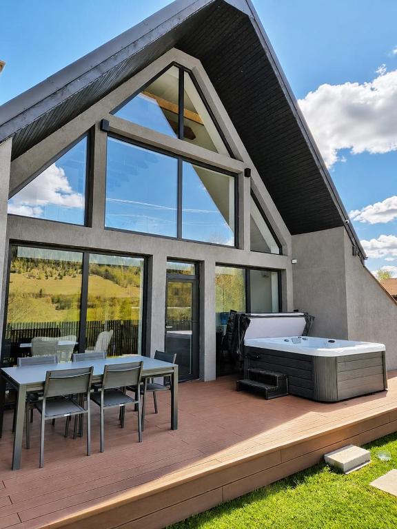 a house with a hot tub on a deck at CBN Cabana in Muntele Cacovei