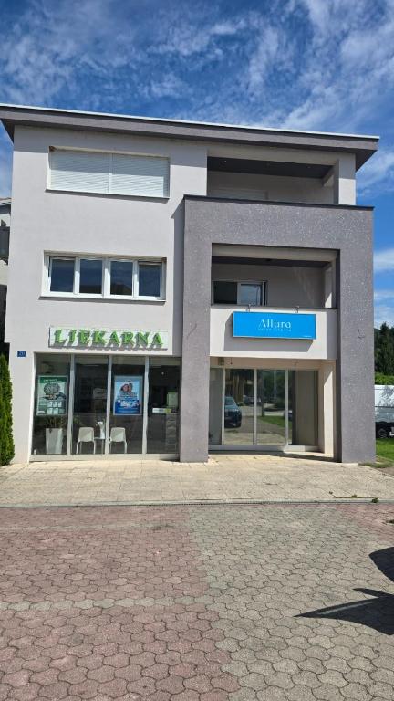 ein großes weißes Gebäude mit einem Eingang, auf dem Stühle stehen in der Unterkunft Apartman Anđa in Široki Brijeg