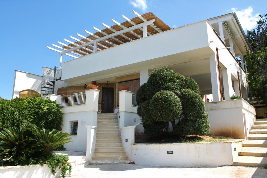 Biały dom ze schodami i drzewami przed nim w obiekcie Baia del Sol Balestrate w mieście Balestrate