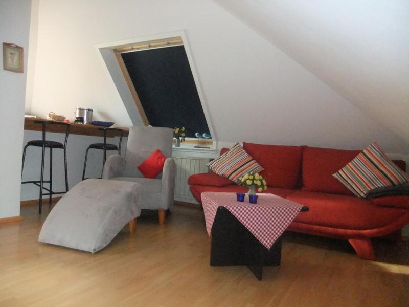 ein Wohnzimmer mit einem roten Sofa und einem Tisch in der Unterkunft Ferienwohnung Max-und-Moritz in Flensburg