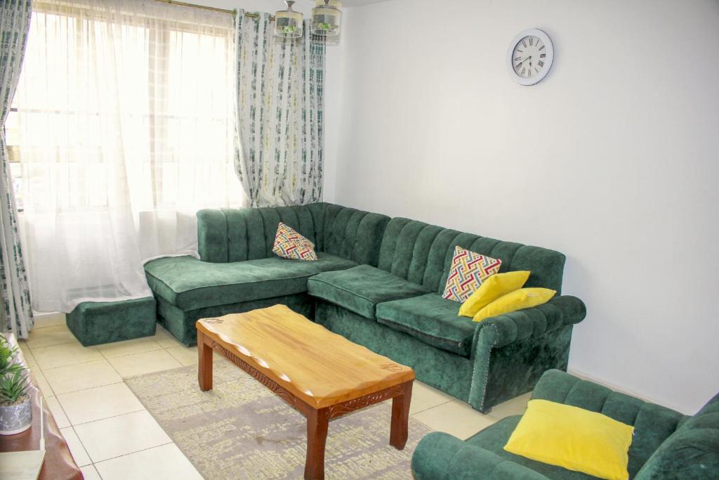 a living room with a green couch and a table at Hidden Gems Homes Modern 2BR Near JKIA, Athi River in Athi River