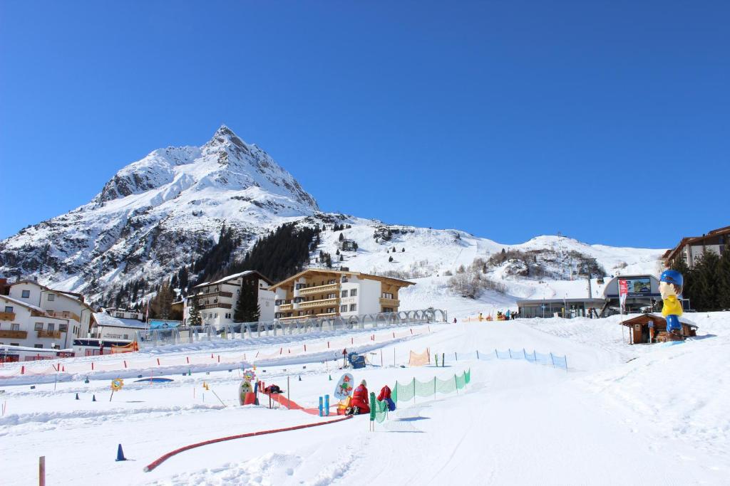 a group of people on a ski slope with a mountain at Hotel Garni Bel-Ami in Galtür