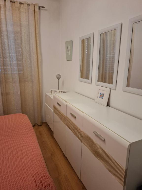 a bedroom with white cabinets and a red bed at Apartman Natali in Buzdohanj