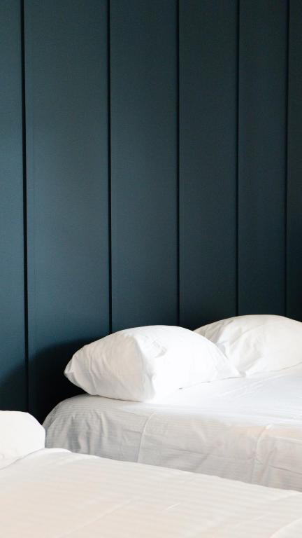 a bed with white sheets and pillows against a blue wall at Auberge Du Roselet in Duingt