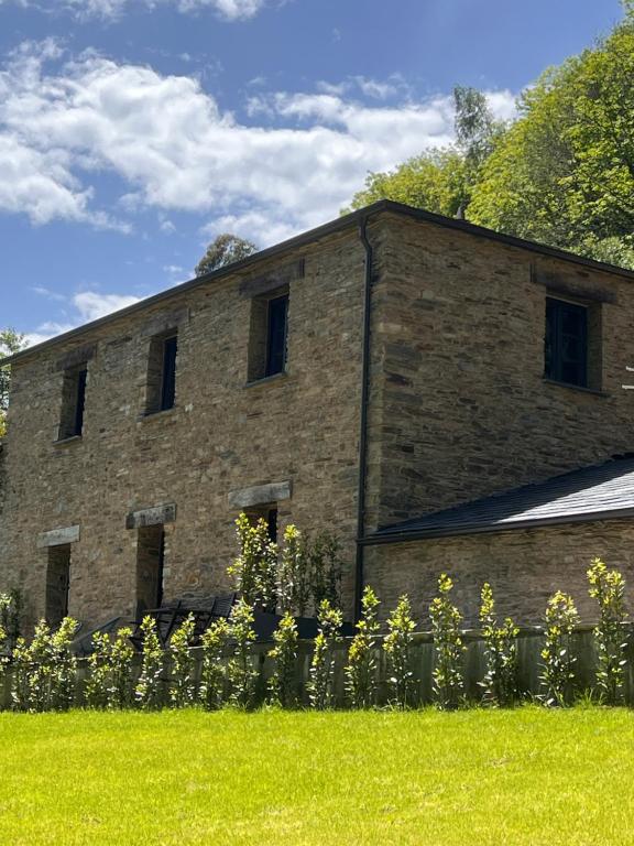 a brick building with windows in a field of grass at Casa Corbeiras Apartamento 1 in A Pontenova