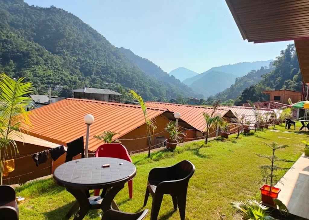 a patio with a table and chairs and mountains at Valley King Resort in Mohan Chatti