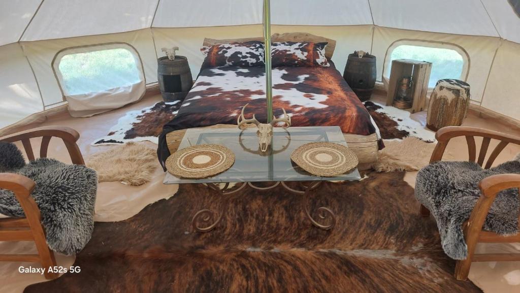 a room with a bed and chairs in a tent at tente western in Le Pener