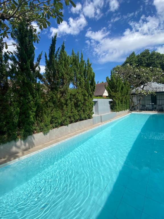 a swimming pool with blue water and trees at La Riva Boutique Hotel in Kamphaeng Phet