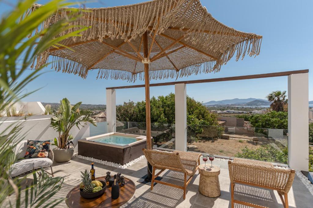 a patio with an umbrella and a table and chairs at Mythodea Luxury Villa Ι Sunset Horizon & Jacuzzi in Naxos Chora