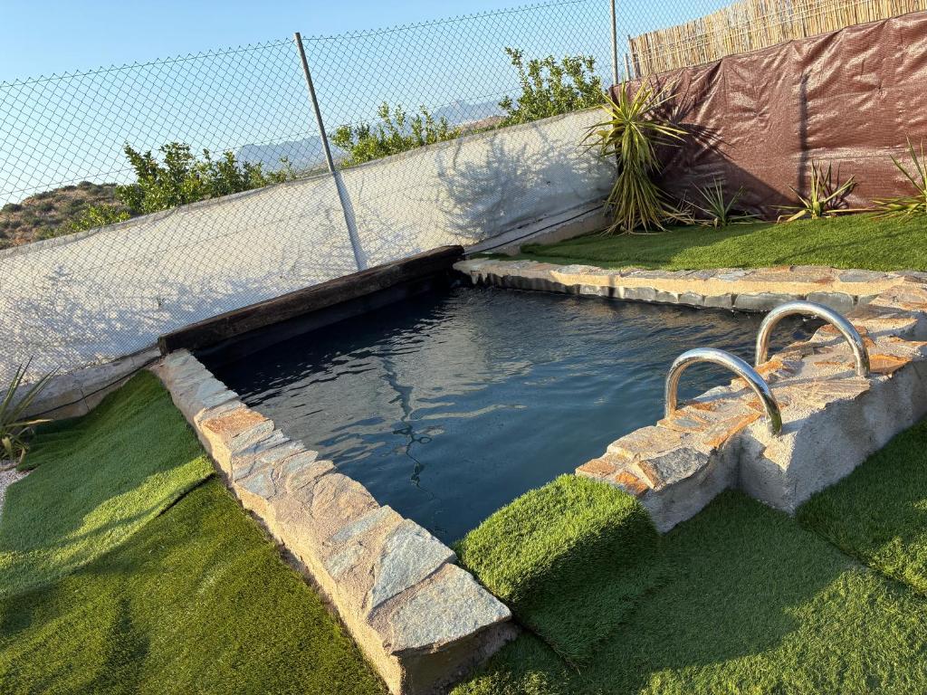 a pool of water next to a fence at Cabaña rural con piscina privada in Orihuela