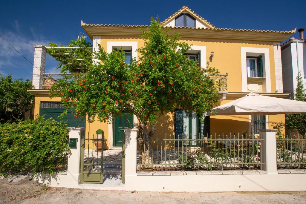 a yellow house with an orange tree in front of it at Palairos Historic Villa in Paleros