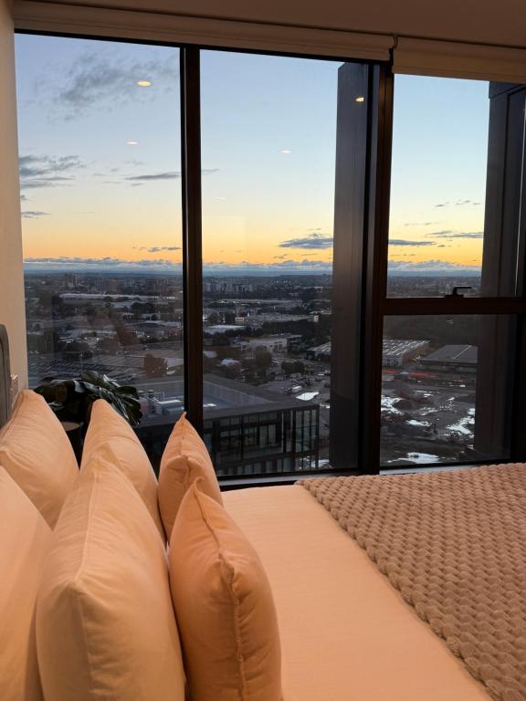 a bedroom with a bed with a view of a city at Luxurious City View with Gym Pool Parking Playground in Sydney