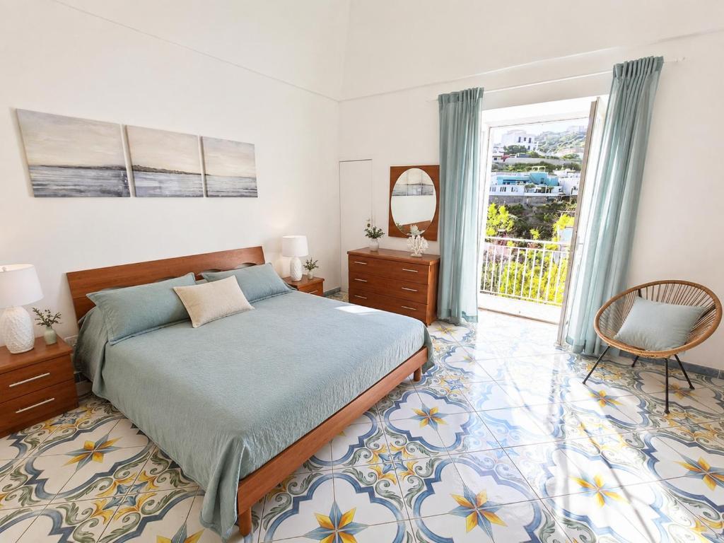 a bedroom with a bed and a chair and a window at Maridea - Chiaia di Luna in Ponza