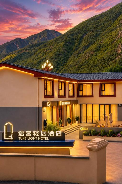 a hotel with a mountain in the background at Tuke Light Hotel Jiuzhaigou 途客轻居酒店九寨沟店 in Jiuzhaigou