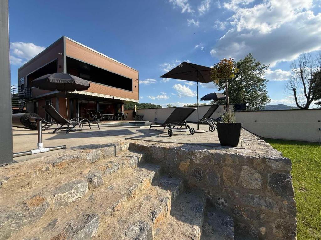 a stone wall with tables and umbrellas in front of a building at AdDrinum in Gornja Koviljača