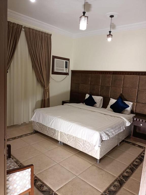 a bedroom with a large white bed with blue pillows at الامتياز in Jeddah