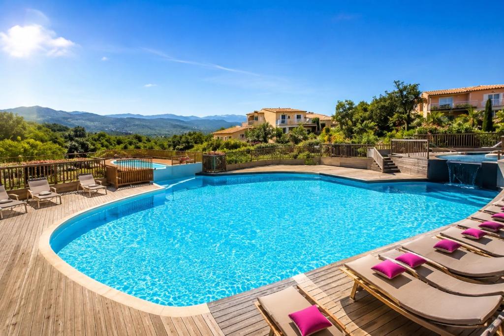 a large swimming pool with chairs and a deck at Mini villa proche plage Santa Giulia in Porto-Vecchio