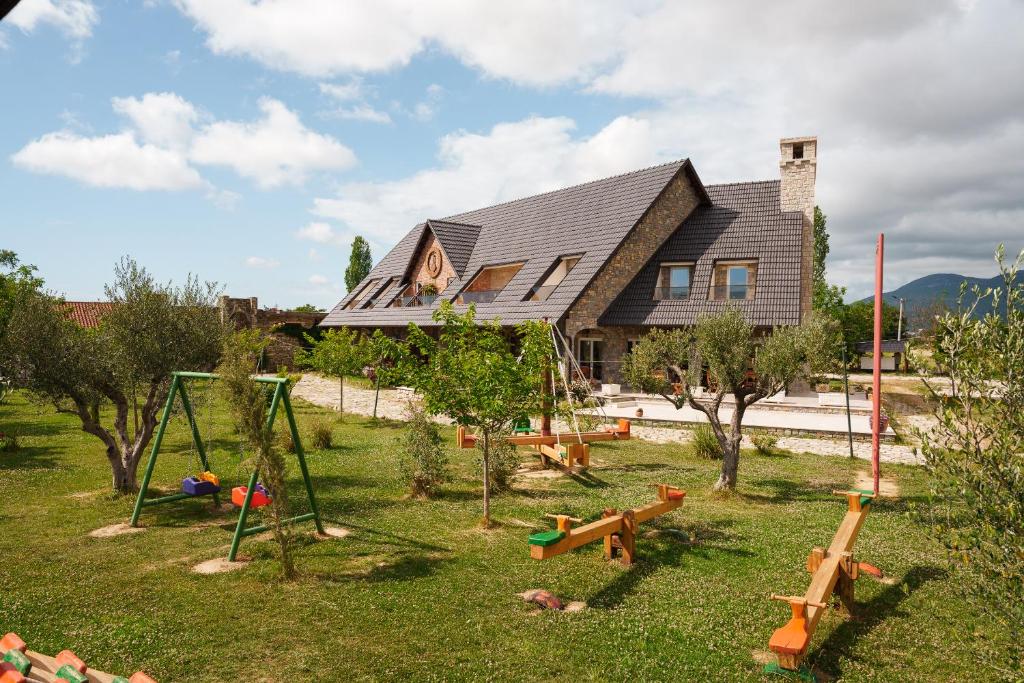 a house with a yard with playground equipment in front of it at Lahuta e Vjeter Agroturizem in Laç