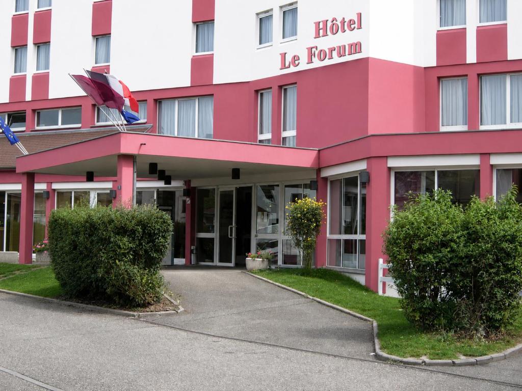 a red and white building with bushes in front of it at The Originals City, Hôtel Le Forum, Strasbourg Nord in Schiltigheim