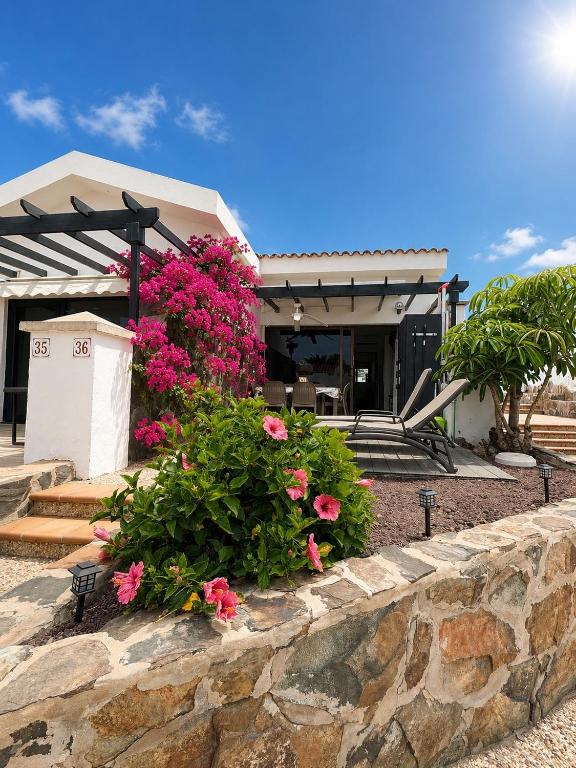 a house with pink flowers on a stone wall at Maspalomas Lago 36 in Maspalomas