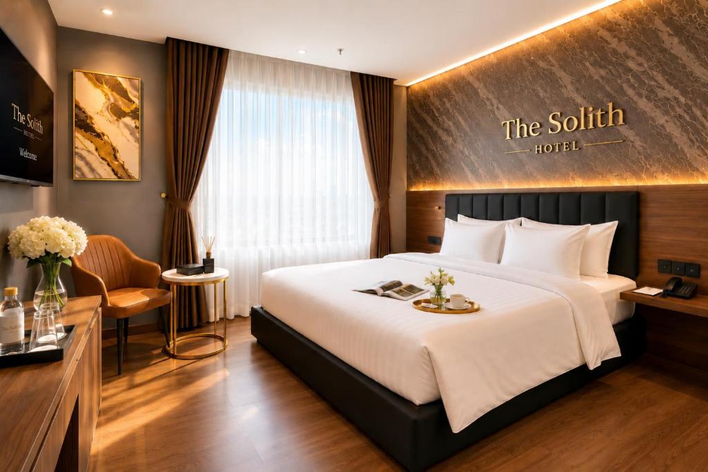 a hotel room with a large bed and a desk at The Solith Hotel Managed By Nicecy in Ho Chi Minh City
