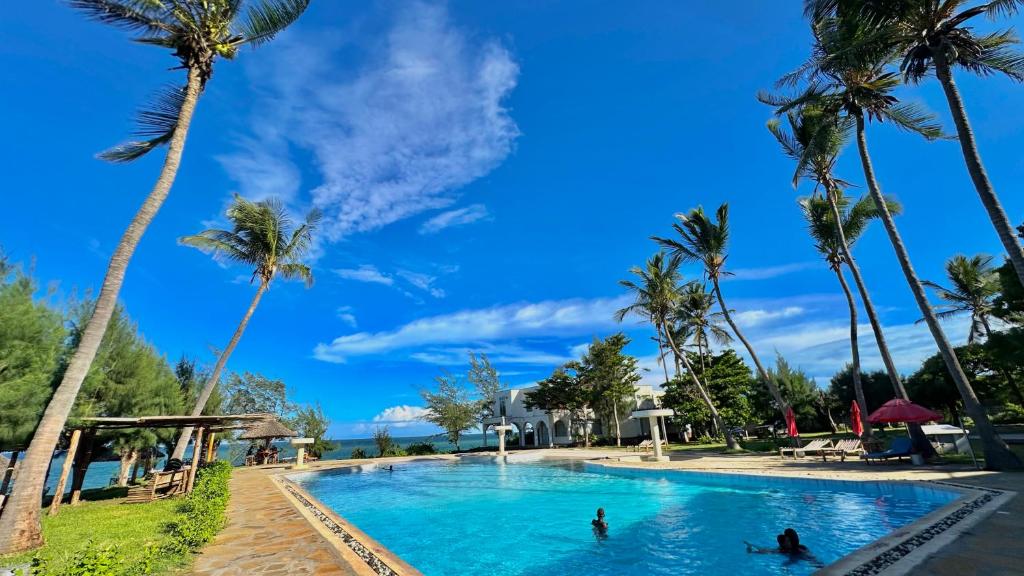 a pool with palm trees and people in the water at Mtwapa Beach Nest D3 in Mtwapa