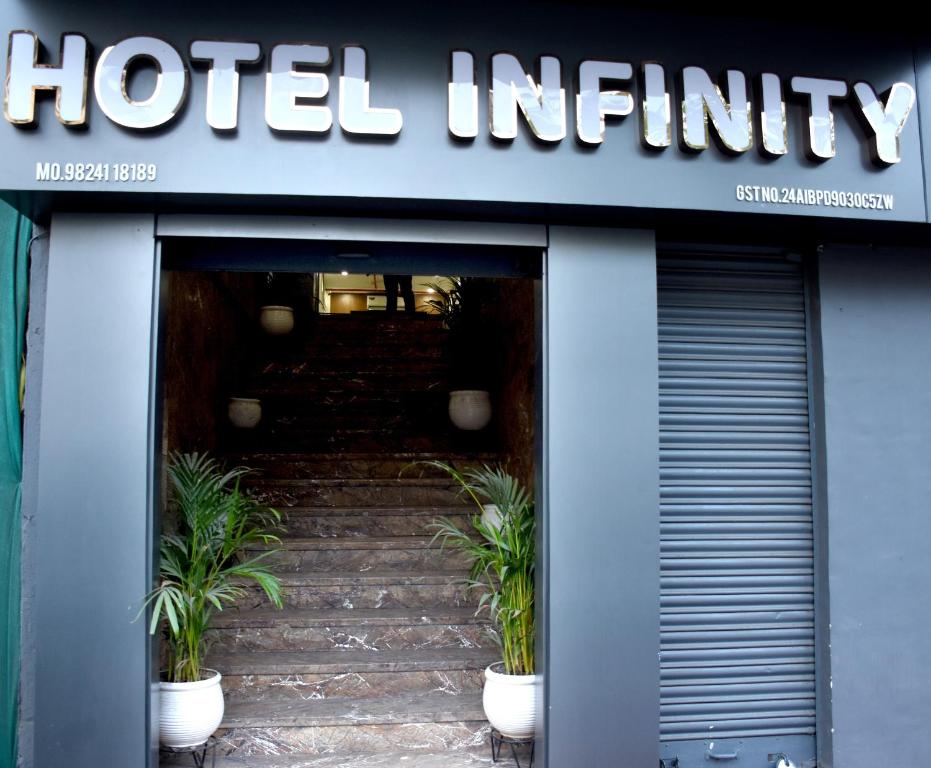 a hotel entrance with potted plants in the doorway at Infinity Hotel in Rajkot