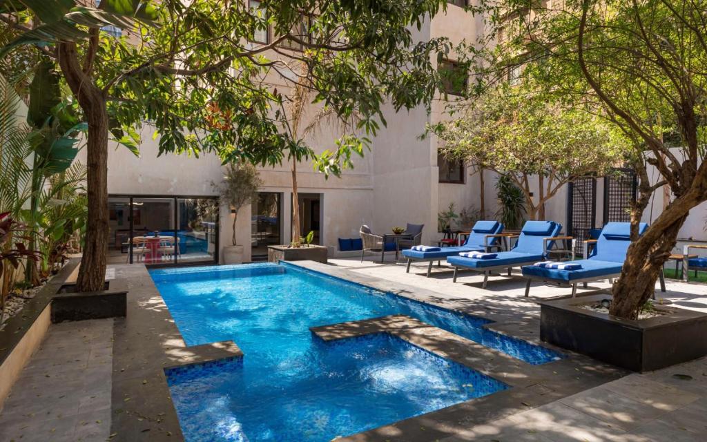a pool in a courtyard with blue chairs and trees at Exclusive savings at 22 by spacey #43 Studio in Maadi in Cairo