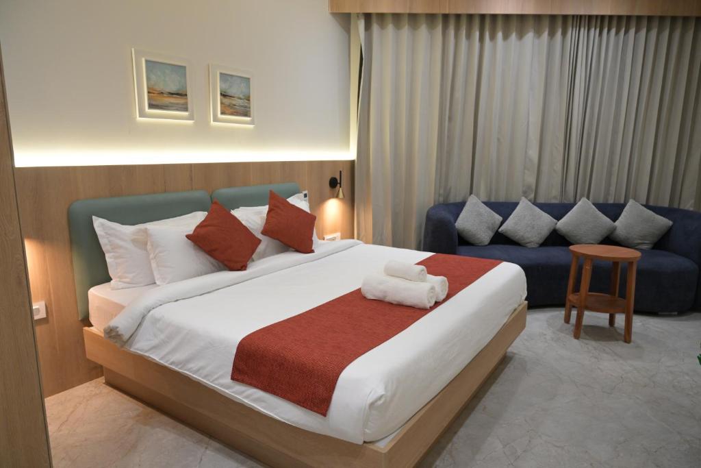 a bedroom with a large bed and a blue couch at The Bhavani Hotel in Dāhod